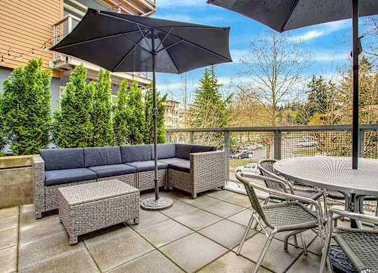A patio with a table, chairs, and an umbrella.