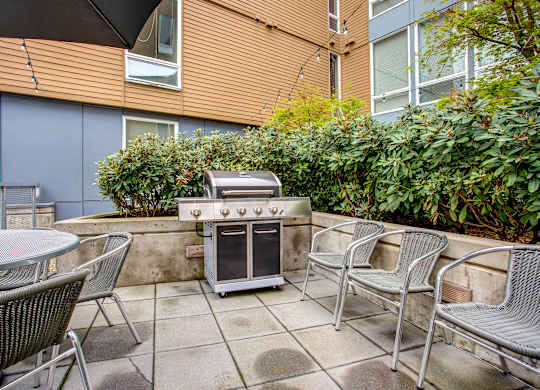 A patio with a grill and chairs.