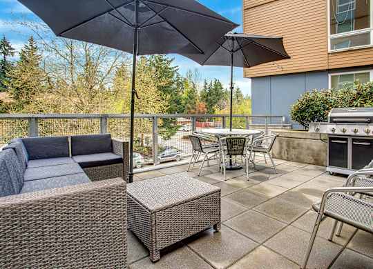 A patio with a couch, chairs, and an umbrella.