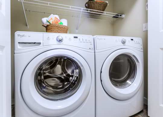 Two white Whirlpool washing machines in a laundry room.