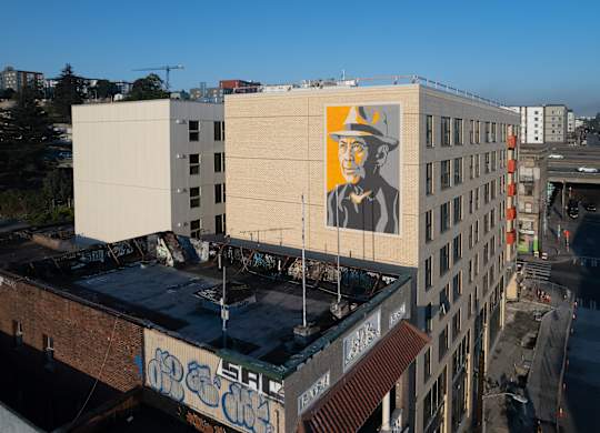 A large mural of a man in a hat is painted on the side of a building.
