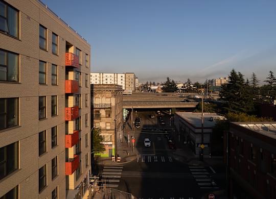 A train is passing under a bridge on a city street.