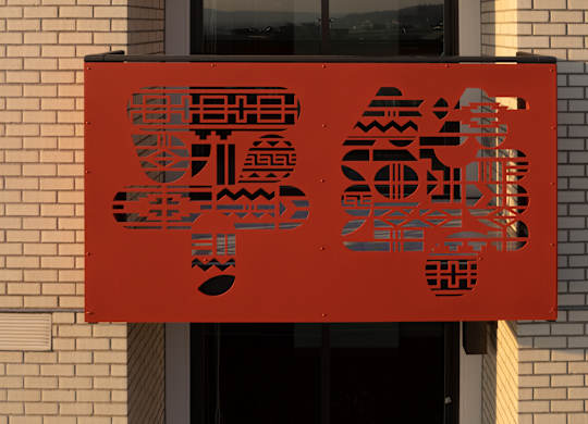 A red sign with black Chinese characters is hanging on a building.
