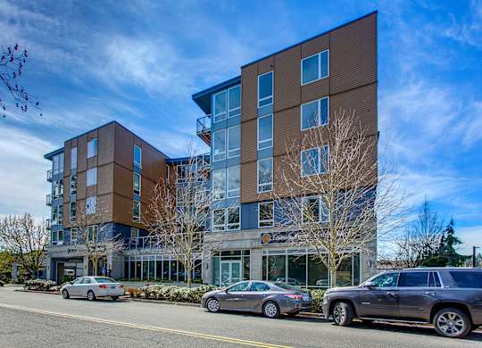 A modern multi-story building with cars parked in front.