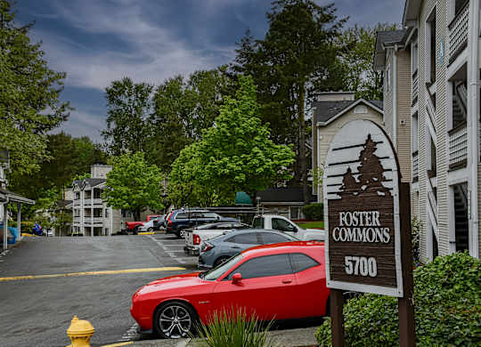A red car is parked in a parking lot with a sign that says