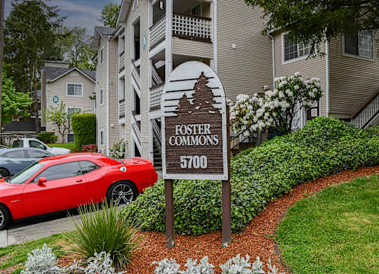 A red car is parked in front of a building with a sign that says "Foster Commons 5700".