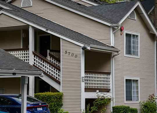 A car is parked in front of a house with the number 5705 on it.
