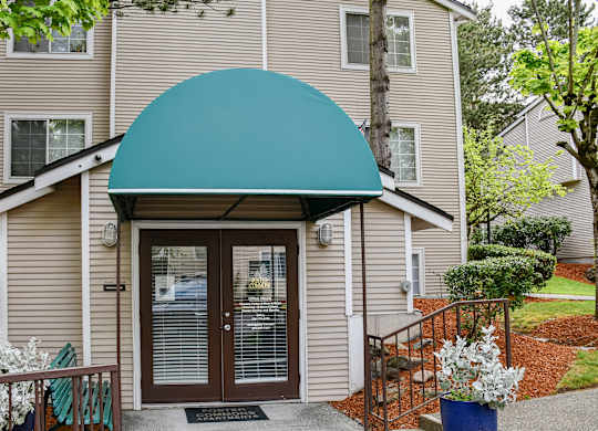 A beige building with a blue awning and a glass door.