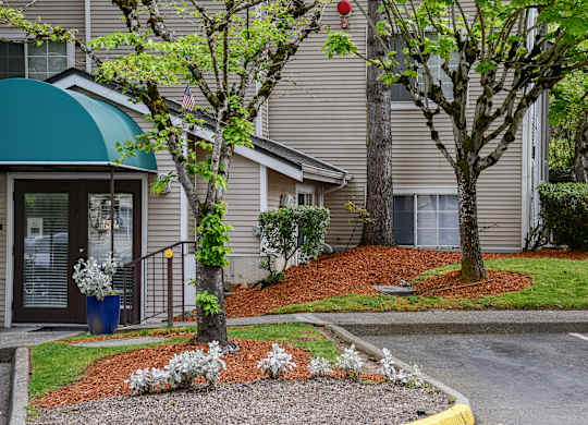 A building with a green awning and a tree with white flowers in front.