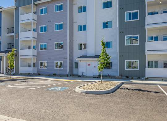 A parking lot in front of a multi-story apartment building.