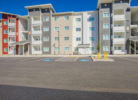 A parking lot in front of a multi-story apartment building.