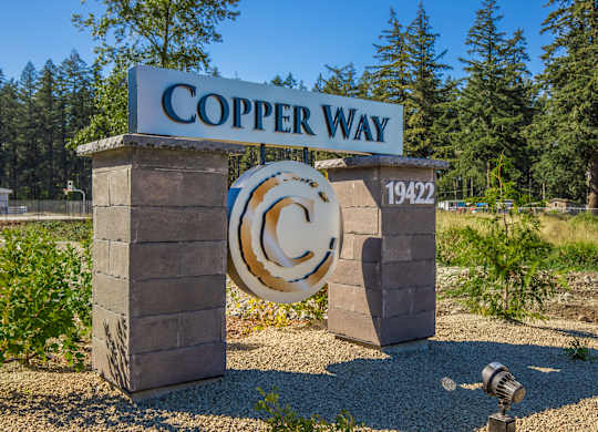 A sign that says Copper Way stands in front of a forest.