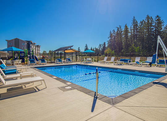 A large swimming pool with a diving board and lounge chairs.