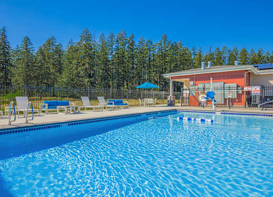 A large swimming pool with a building and trees in the background.