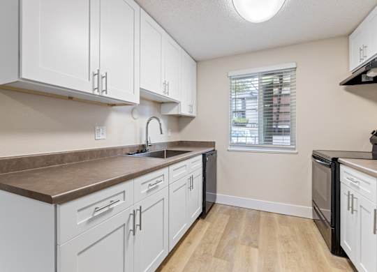 A kitchen with white cabinets and a brown countertop.