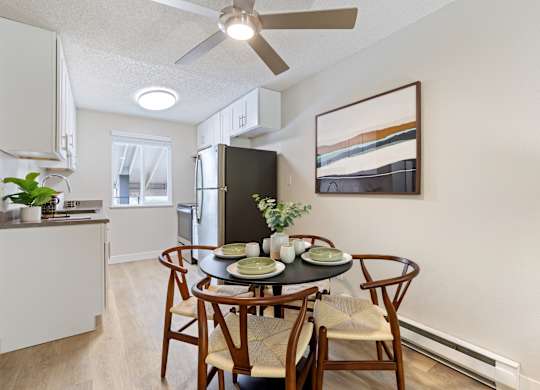 A dining room with a table set for two and a ceiling fan.
