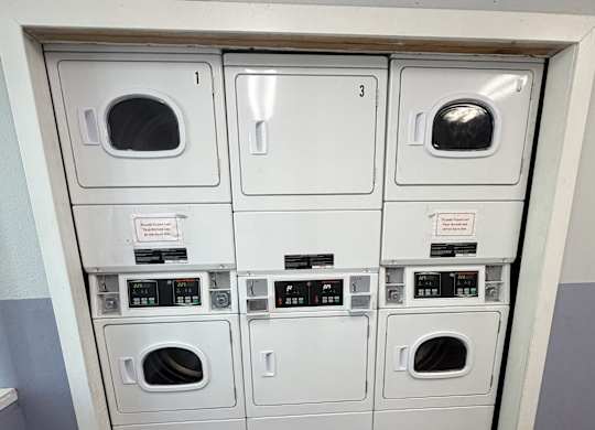 A row of washing machines are lined up in a wall.