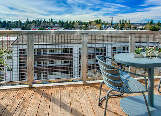 A balcony with a table and chairs overlooking a building.