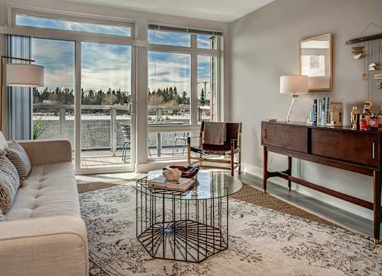 A living room with a couch, a coffee table, and a large window.