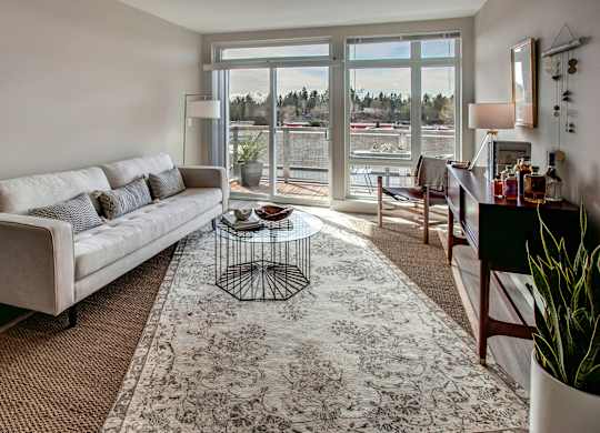 A living room with a couch, coffee table, and a view of the outside.