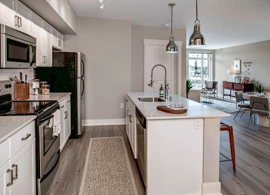A kitchen with black and white appliances and wooden floors.