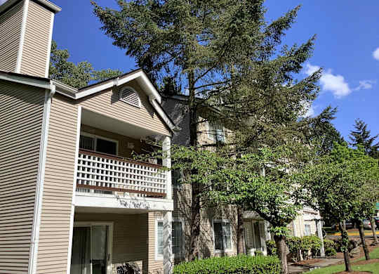 A house with a balcony and a tree in front.