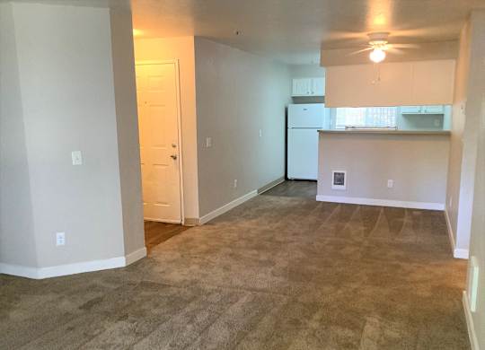 A room with a carpeted floor and a ceiling fan.