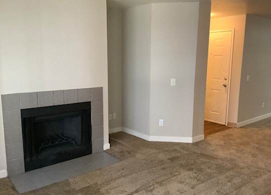 A black fireplace in a room with a carpeted floor.