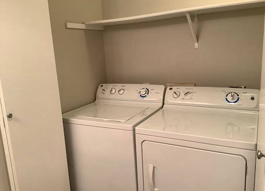 Two white washing machines in a small laundry room.