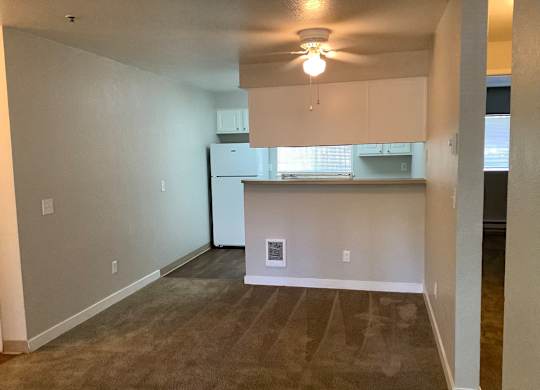 A kitchen area with a refrigerator, cabinets, and a ceiling fan.