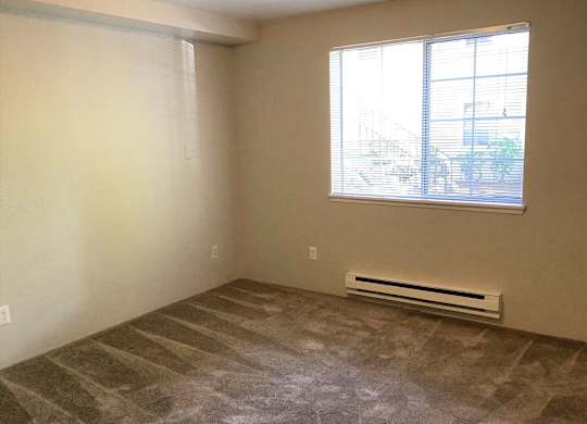 A room with a window and a heater on the floor.