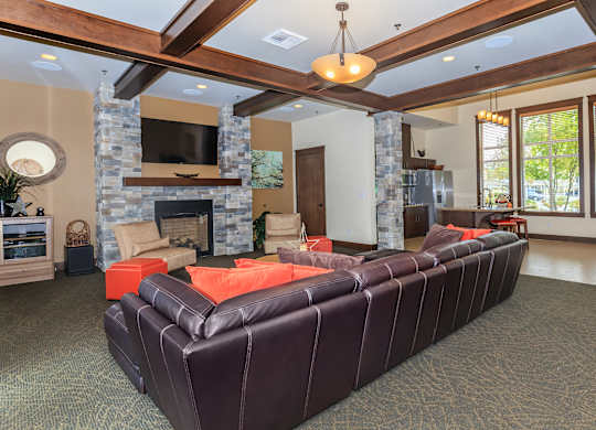 A living room with a stone fireplace and a brown leather couch.