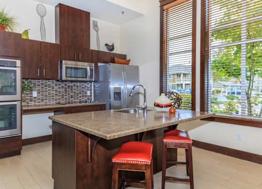 A kitchen with a brown counter top and red bar stools.