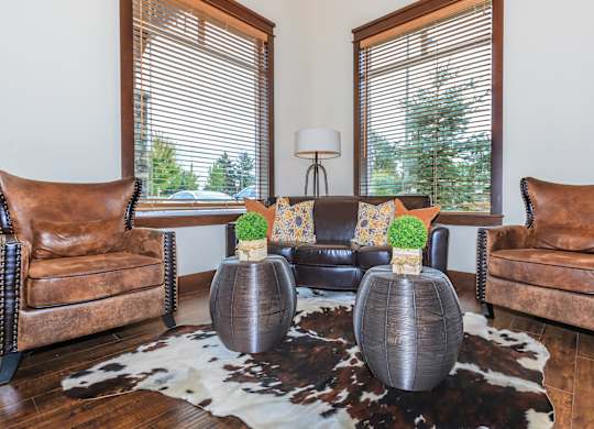 A living room with brown leather chairs and a cowhide rug.