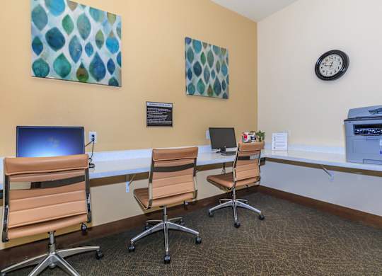 A room with a computer desk and chairs.