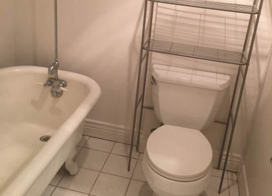 A white toilet sits next to a white bathtub in a bathroom.