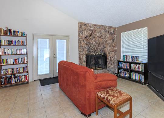 A living room with a red couch, a fireplace, and a bookshelf.