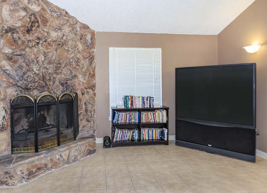 A living room with a stone fireplace and a flat screen TV.