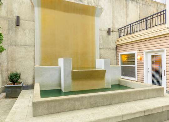 A modern house with a yellow wall and a small pool in front.