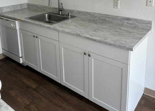 A kitchen with white cabinets and a marble countertop.
