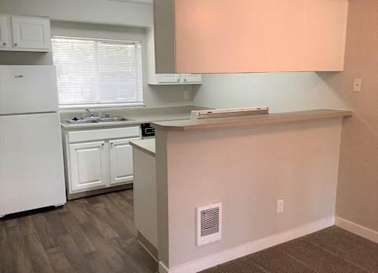 A kitchen with white appliances and a window.