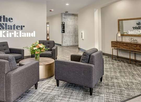 A waiting area with grey chairs and a wooden desk.