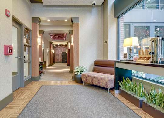 A hallway with a red fire alarm on the wall.
