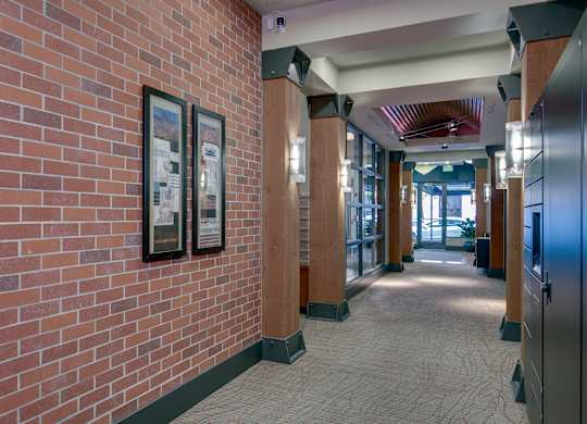A hallway with a brick wall and framed pictures on it.