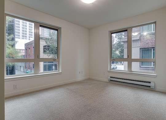 A spacious room with two windows overlooking a cityscape.