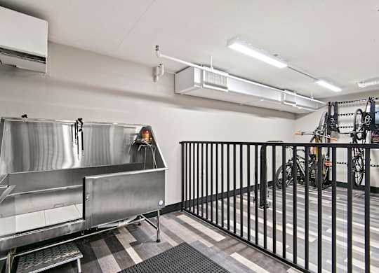 A large stainless steel sink in a room with a black fence.