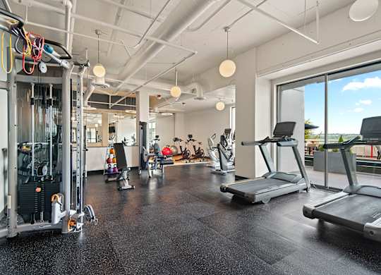 Apartments for Rent in Tacoma, WA - The Orion - Fitness Center With Treadmills, Strength Training Equipment, Rubber Flooring, Modern Lighting, and Large Windows.