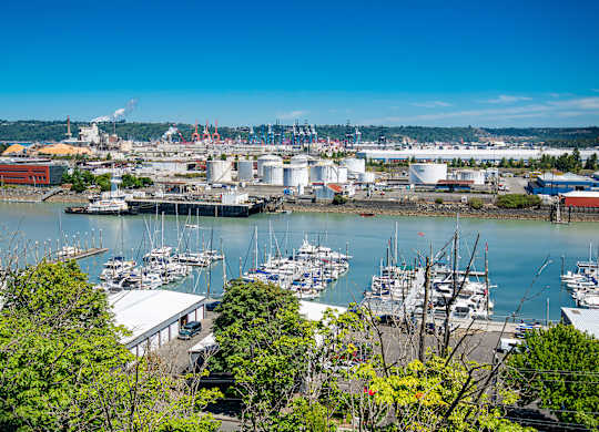 A view of a harbor with boats and industrial buildings.