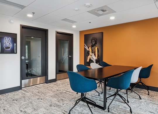A conference room with a table and chairs and a painting on the wall.
