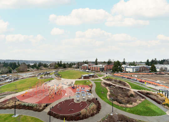 A playground with a red slide and a green hill.